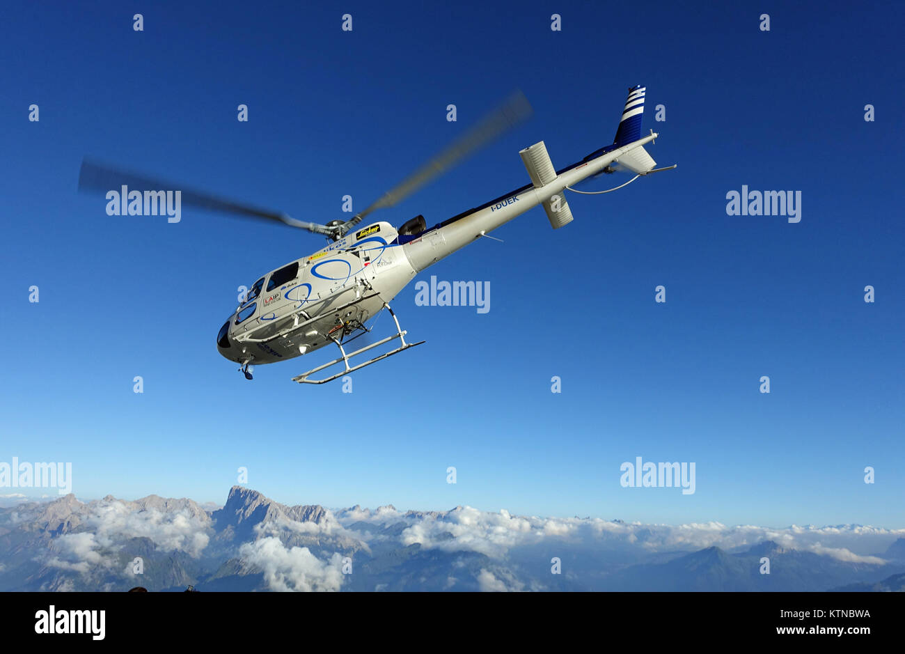 Cet hélicoptère est l'atterrissage sur le sommet d'une haute montagne où les cavaliers sont de BASE Wingsuit s'en sortir. Banque D'Images