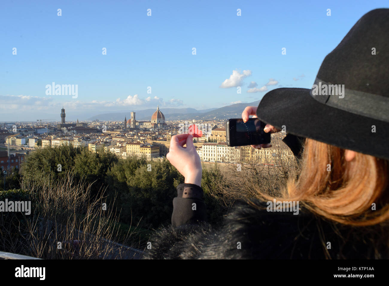 Vue de derrière d'une jeune fille avec un chapeau qui prend une photo à la Florence panorama vu de la Piazzale Michelangelo avec un cœur rouge dans la main Banque D'Images