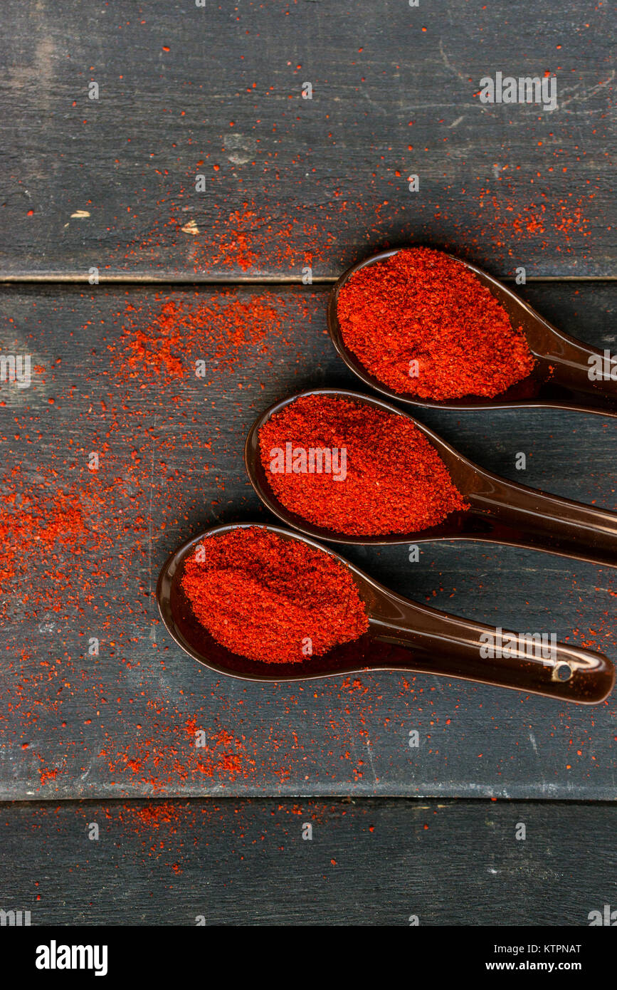 Vue de dessus trois cuillères en plastique remplis d'épices paprika rouge foncé sur fond de bois Banque D'Images Vue de dessus trois cuillères en plastique remplis d'épices paprika rouge foncé sur fond de bois Banque D'Images