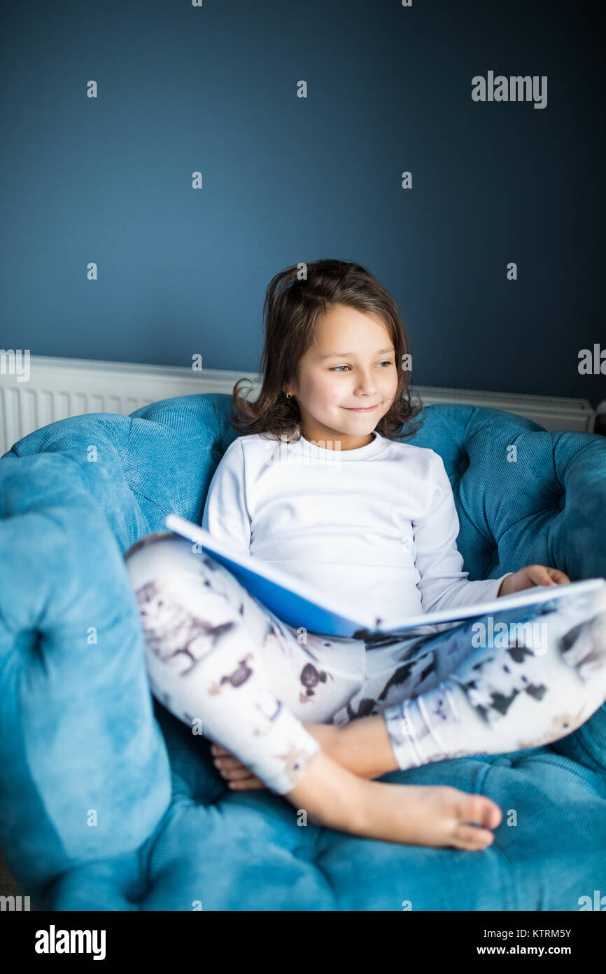 Happy Funny Girl la lecture d'un livre et lecture au lit. Les enfants jouent à la maison. Pépinière blanc. Enfant dans une chambre ensoleillée. La lecture et l'étude d'enfants. Interio Banque D'Images