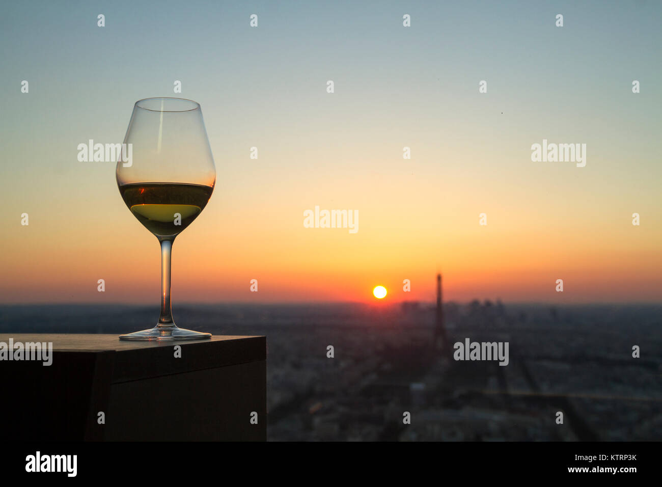 Verre de vin blanc avec vue sur la ville de paris au coucher du soleil Banque D'Images