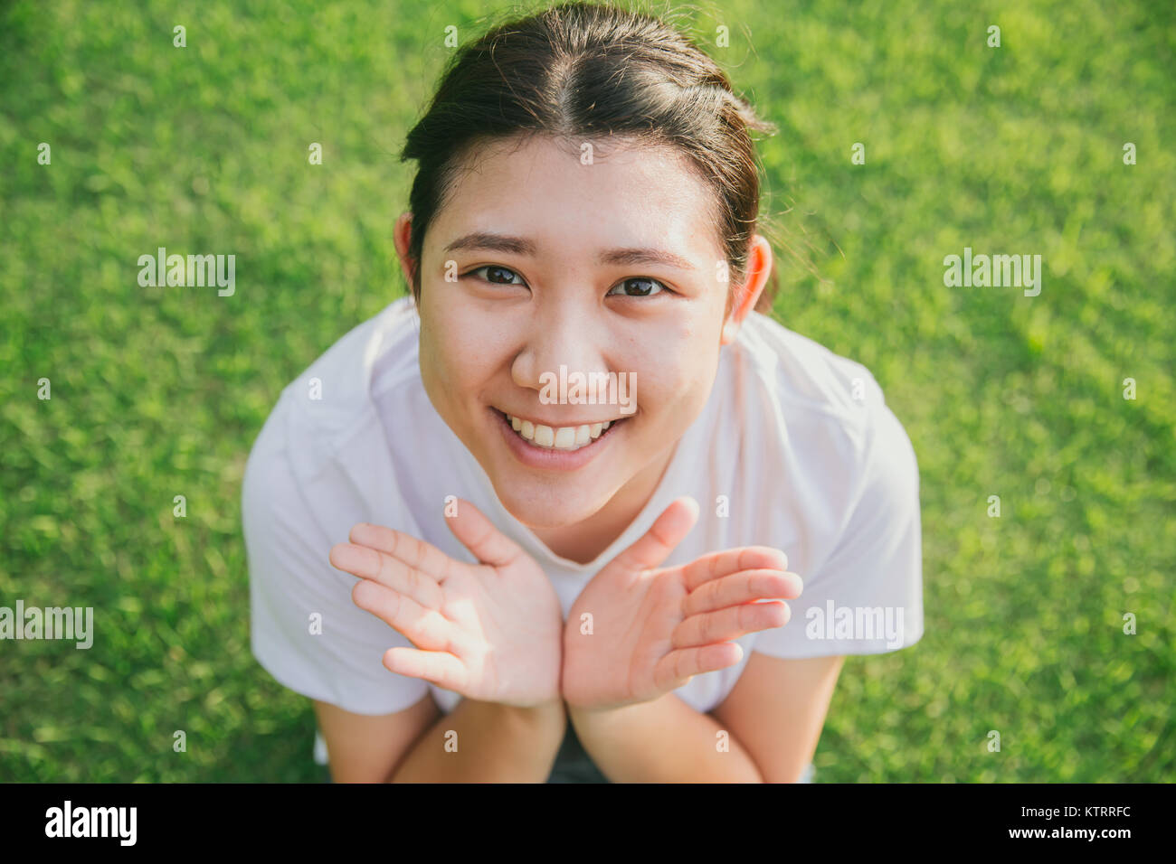 Jeune ado asiatique innocent sourire avec fond d'herbe verte Banque D'Images