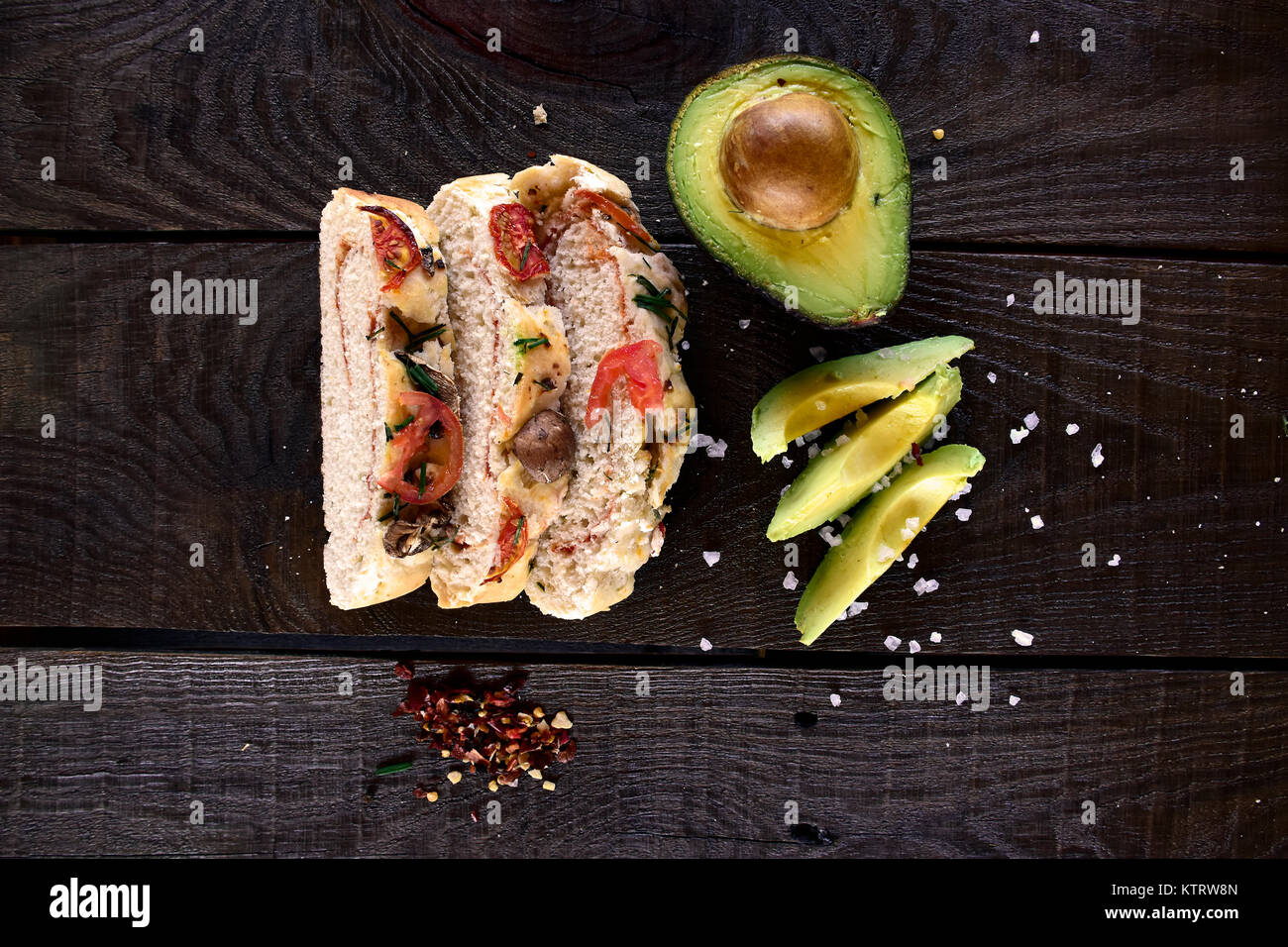 Pain maison garnie de champignons et de tomates séchées au soleil à côté de l'avocat et le gros sel sur un fond de bois rustique, photographié d'en haut'''' Banque D'Images