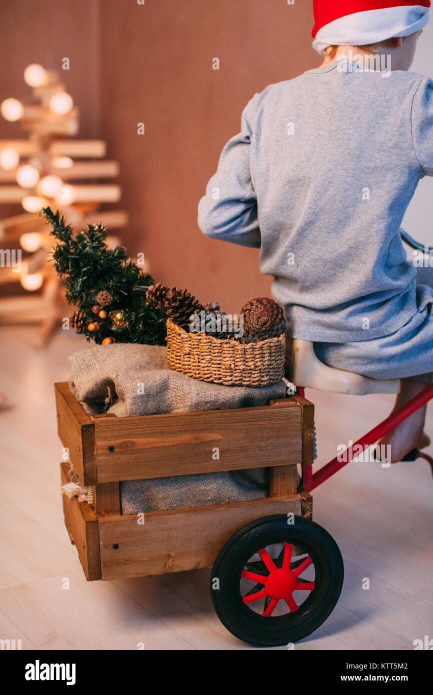 Boy wearing a santa hat ricing un tricycle avec décorations de Noël Banque D'Images