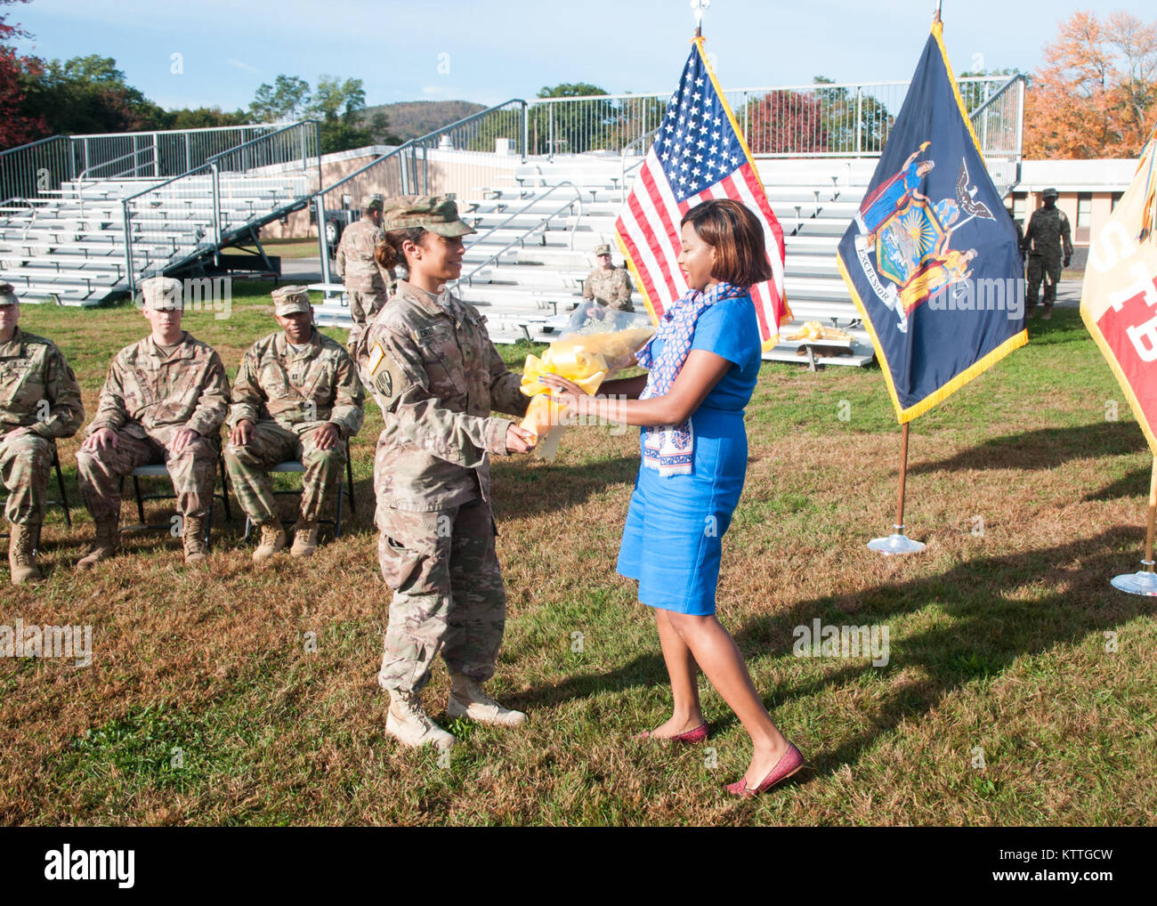 La CPS. Juleinny Cruz présente un bouquet de roses jaunes à Alexis Daramola, épouse du nouveau commandant du 369ème, HHC Cpt. Oyeyemi Daramola, au cours d'une cérémonie de passation de commandement au camp Smith, NY, le 22 octobre 2017. L'appareil retourné cet été, de la réussite d'un déploiement de 9 mois au Moyen-Orient. (Photo par le Sgt. Jeremy Bratt) Banque D'Images