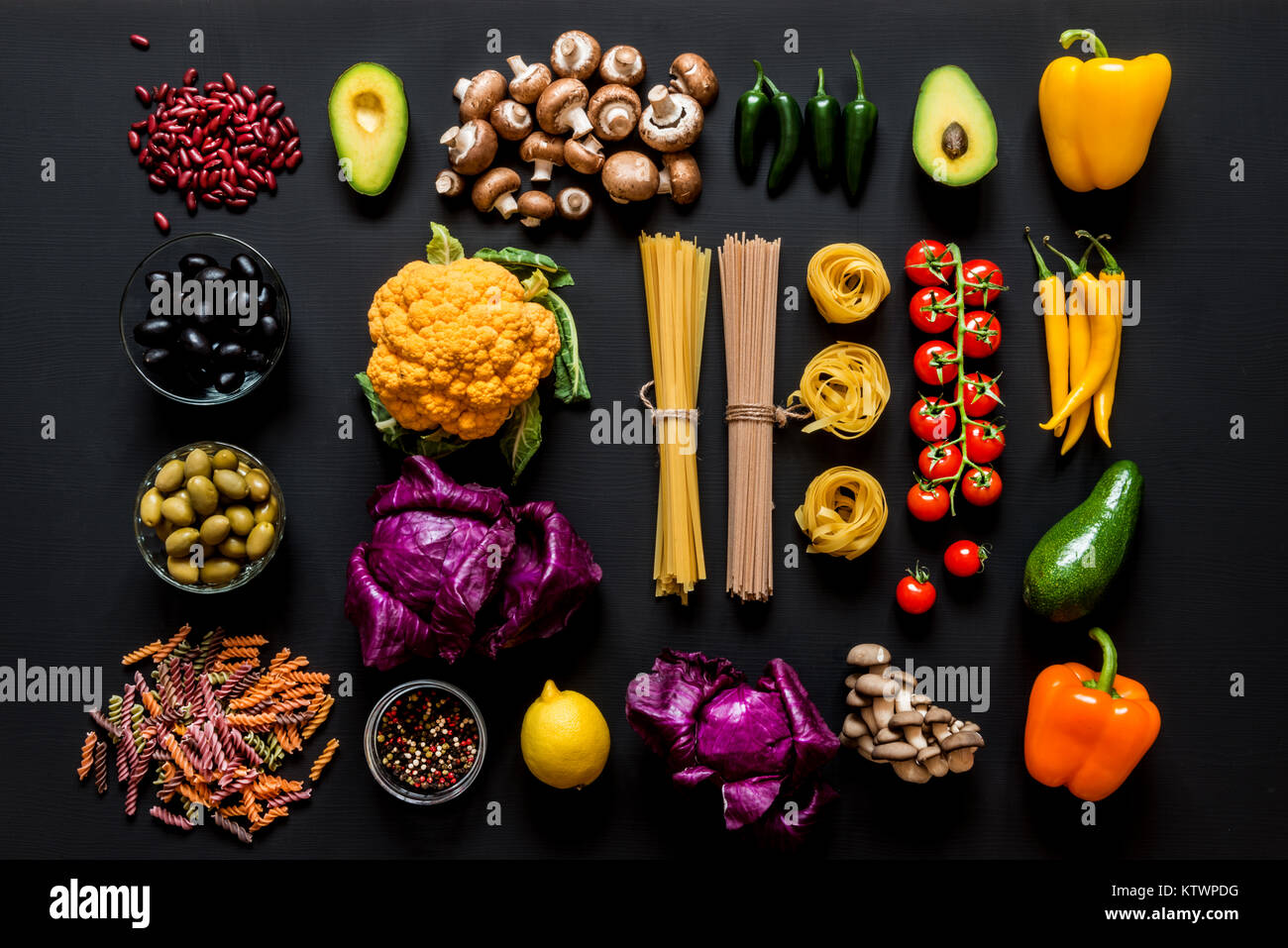 Différents ingrédients crus frais colorés pour la cuisine végétarienne saine sur un fond noir. Mise à plat, vue du dessus. Banque D'Images