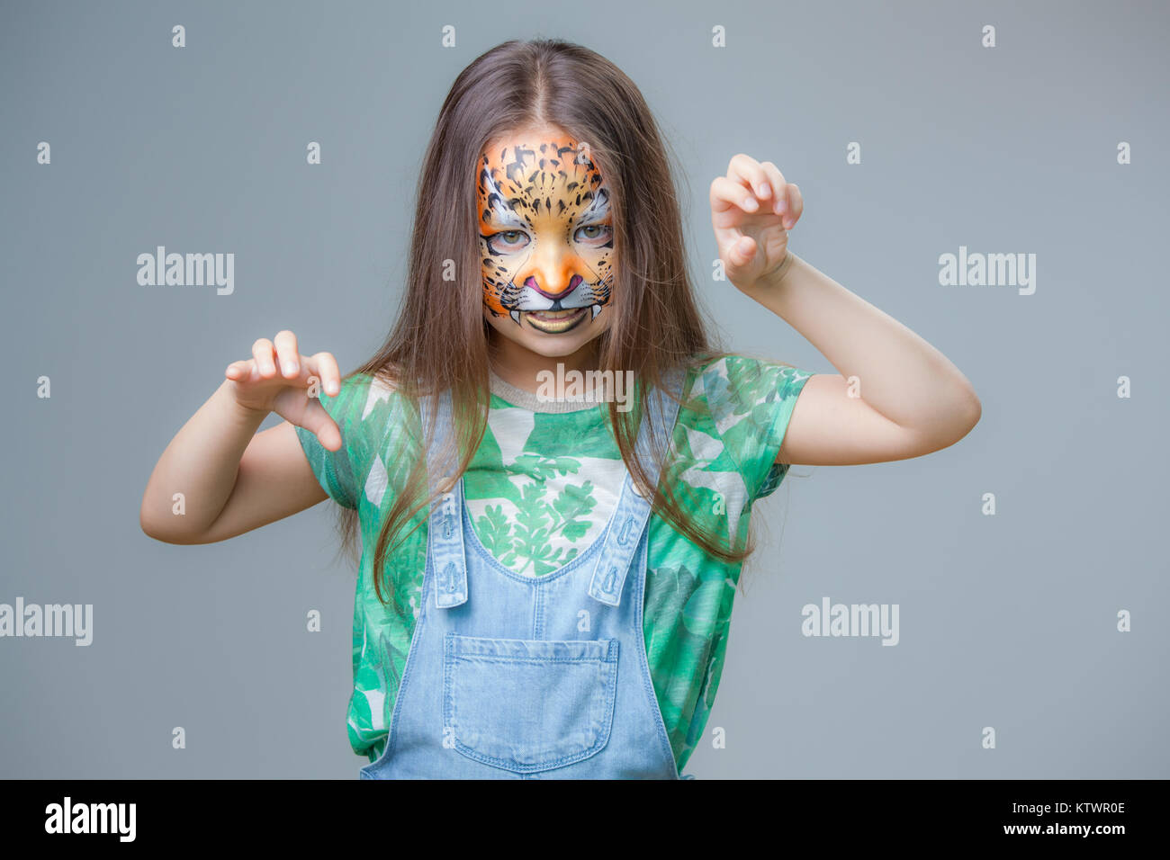 Portrait d'une petite fille avec un tigre peint sur son visage sur un fond gris Banque D'Images