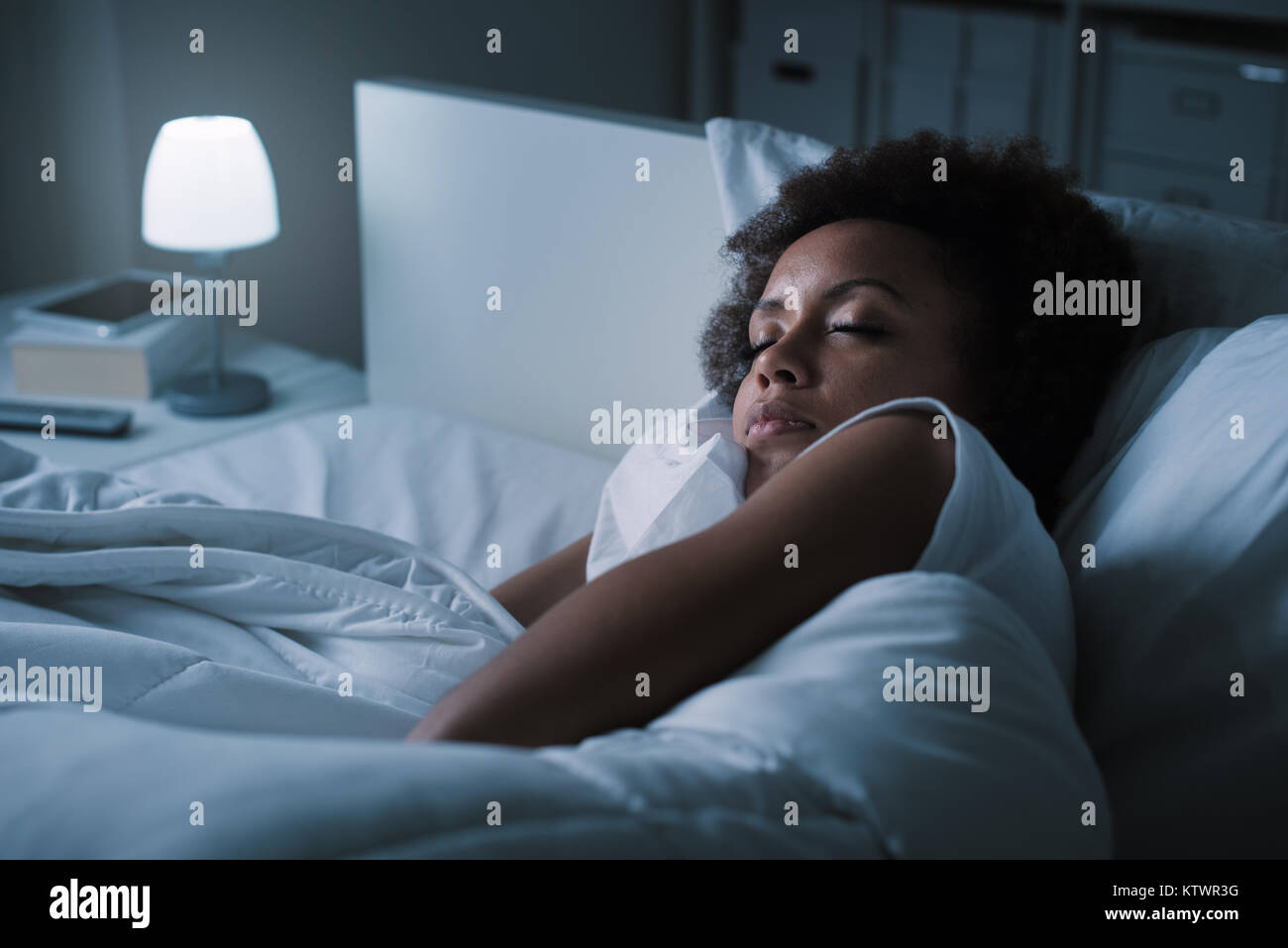 Jeune femme africaine de dormir dans son lit la nuit, elle se repose avec les yeux fermé Banque D'Images