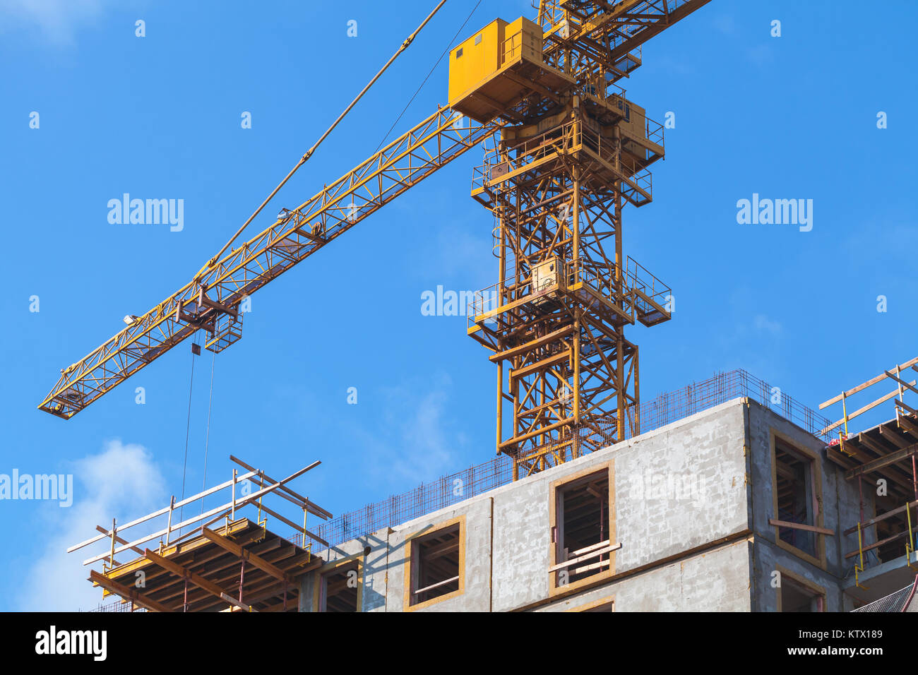 Grue jaune fonctionne, béton chambre avec balcon de la carcasse est en construction Banque D'Images