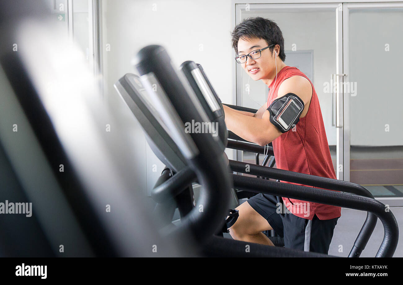 Bel homme sur l'exécution de la machine avec l'écoute de la musique pour vous détendre dans une salle de sport, salle de remise en forme Banque D'Images