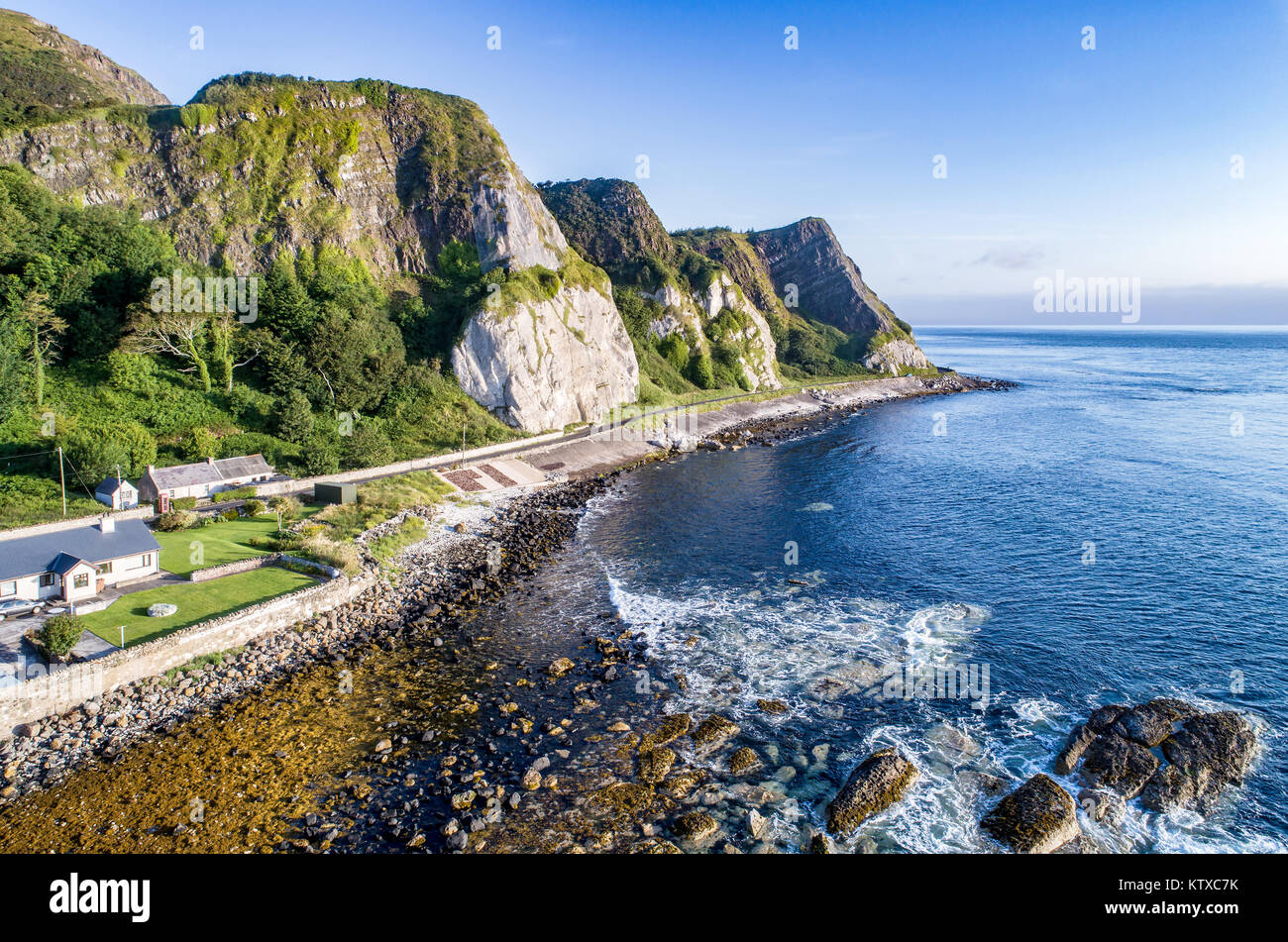 La côte orientale de l'Irlande du Nord avec des falaises et route côtière d'Antrim, alias Causeway Route Côtière. Vue aérienne au lever du soleil Banque D'Images