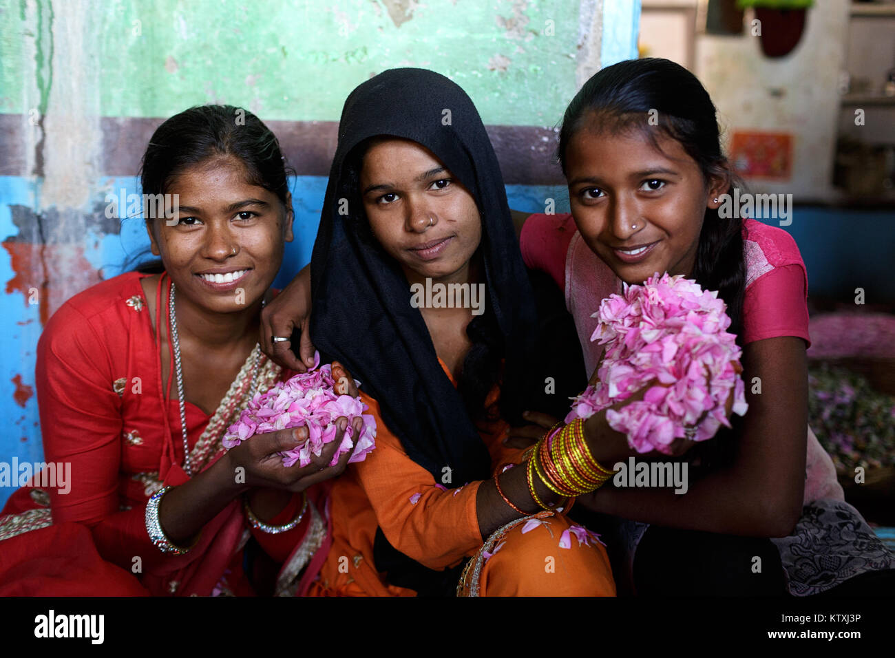 Trois jeune filles indiennes en vêtements traditionnels holding flower petals dans leur maison dans le village proche de Pushkar, Rajasthan, Inde. Banque D'Images