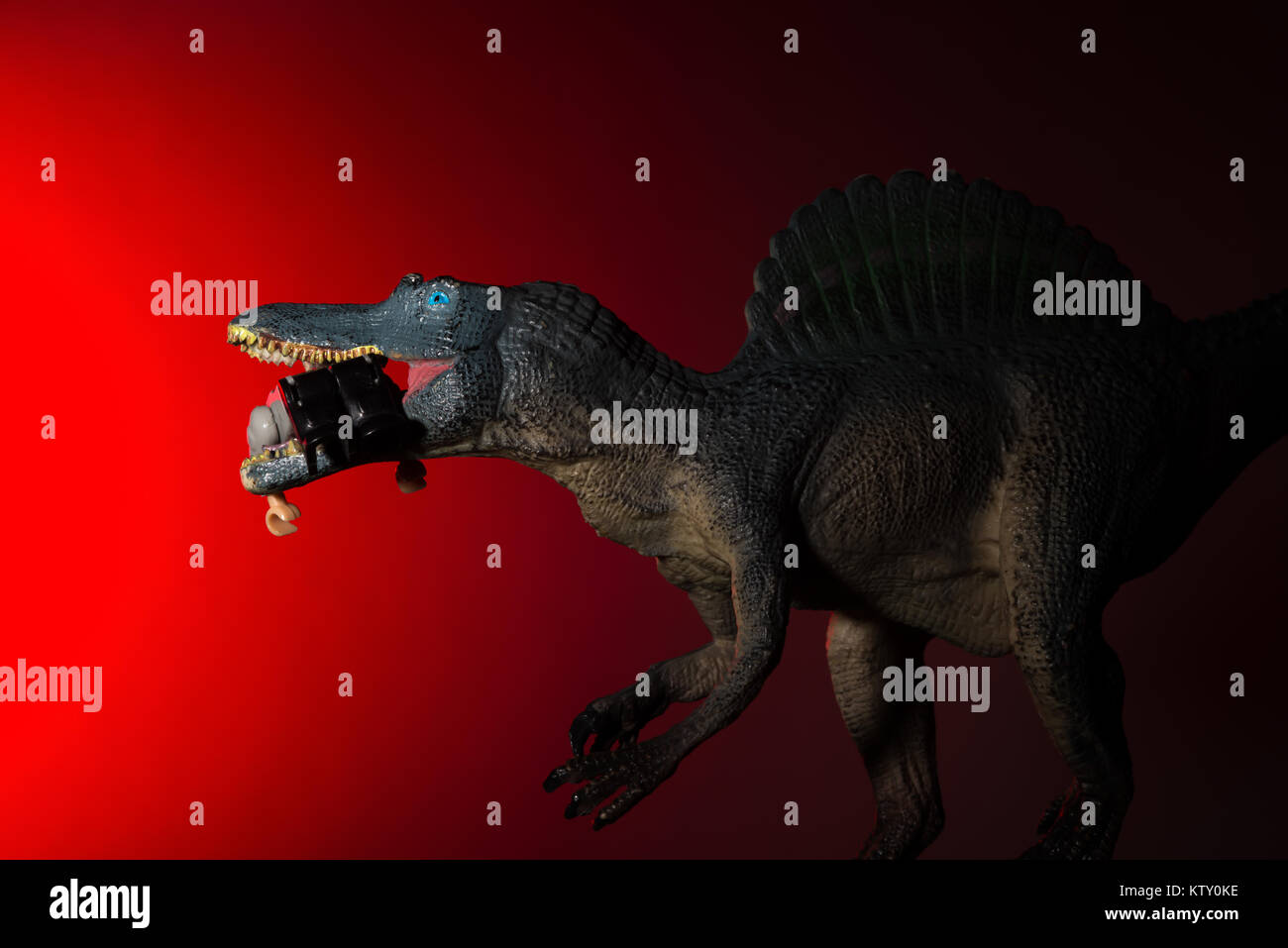Spinosaurus mordant un corps humain avec spot de lumière sur la tête et voyant rouge sur l'arrière-plan Banque D'Images