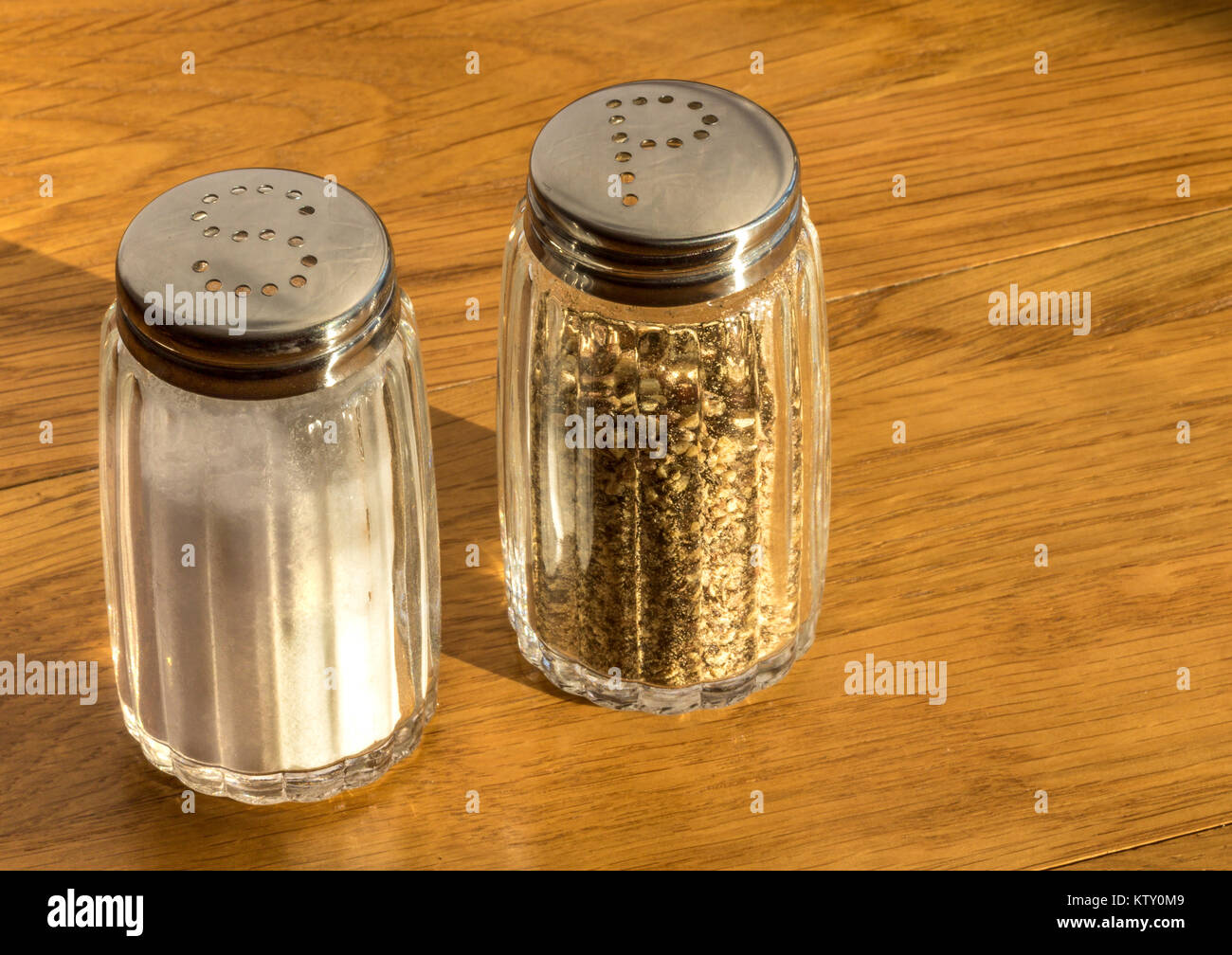 Close up de salière et poivrière en verre ou des pots de sel et de poivre sur une table en bois ,très commun coin condiments vu sur n'importe quelle table aux heures des repas Banque D'Images