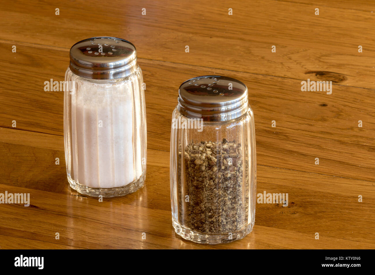 Close up de salière et poivrière en verre ou des pots de sel et de poivre sur une table en bois ,très commun coin condiments vu sur n'importe quelle table aux heures des repas Banque D'Images