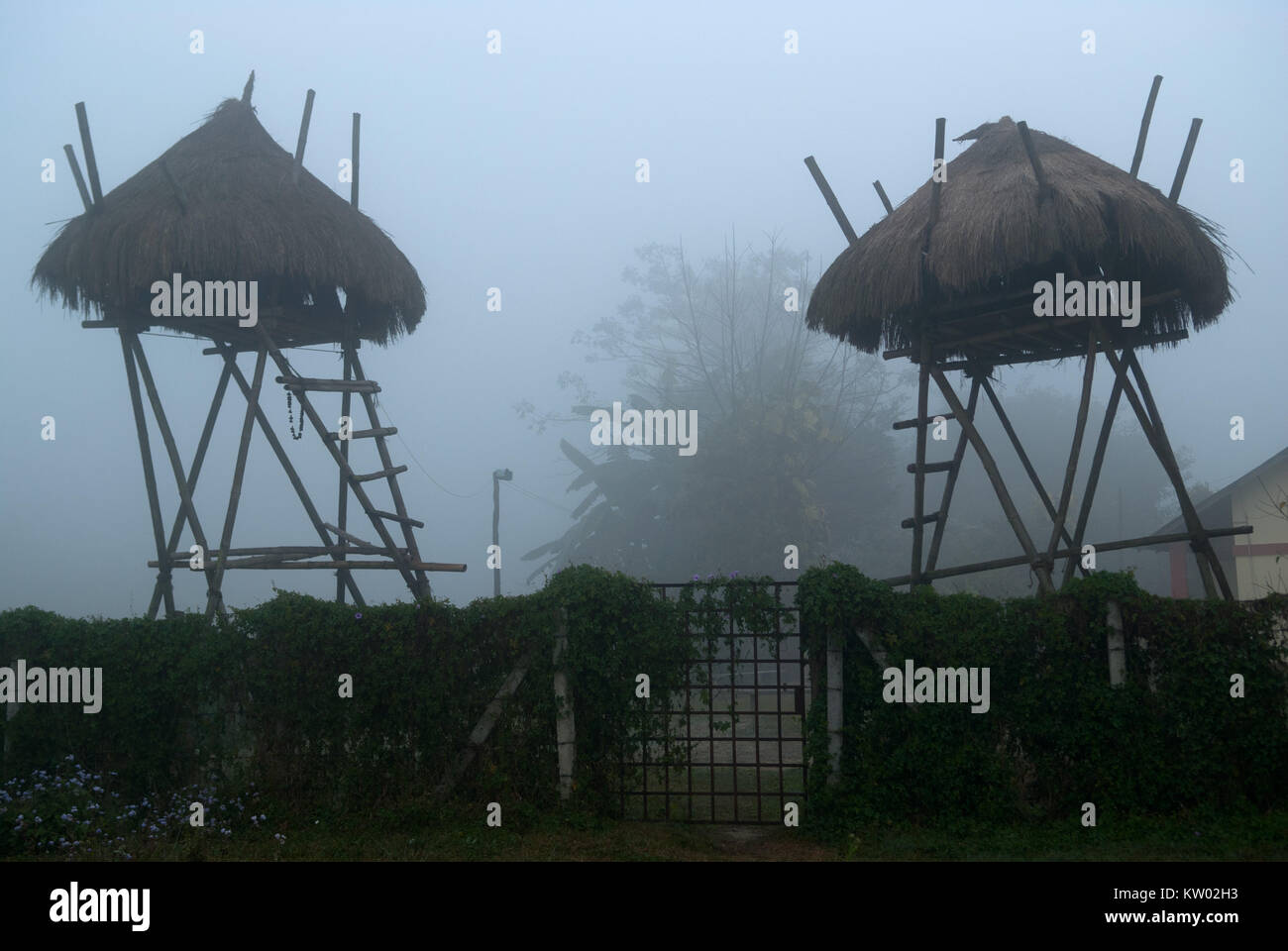 Abris de chasseurs et les tuteurs à proximité d'une clôture en bois, bungalows sur pilotis, haut de crépuscule et de brume. Banque D'Images