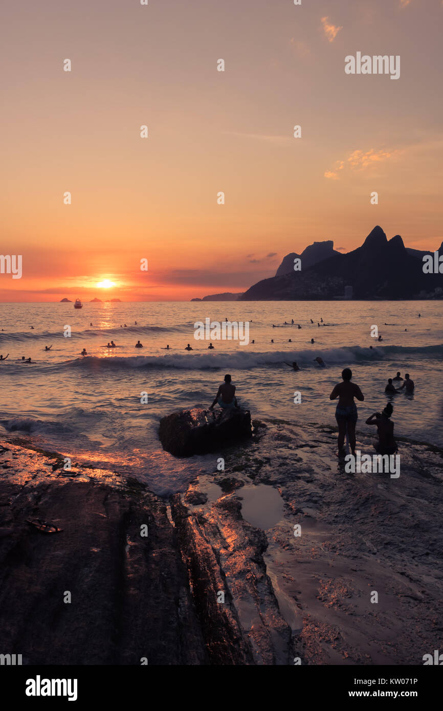 Le soleil est en ordre décroissant vers le bas au-dessous de l'horizon qui est l'une belle orange, rouge et jaune de la lumière. Il y a d'ossature d'une foule de personnes Banque D'Images