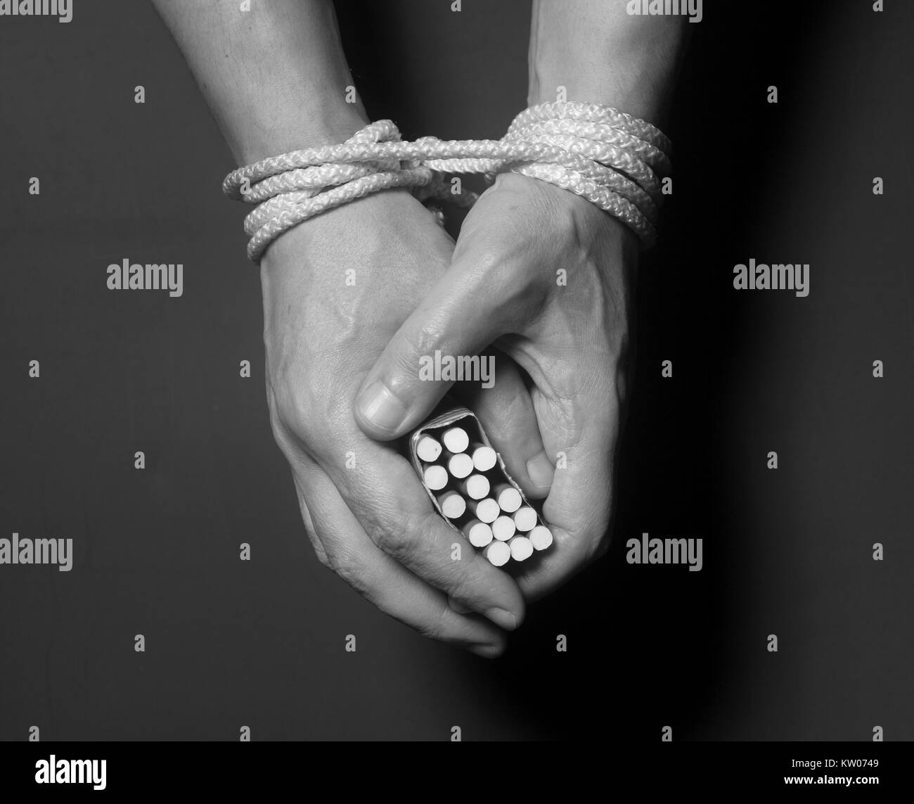 La dépendance au tabac. Image main d'hommes sur les cigarettes attachés avec une corde Banque D'Images