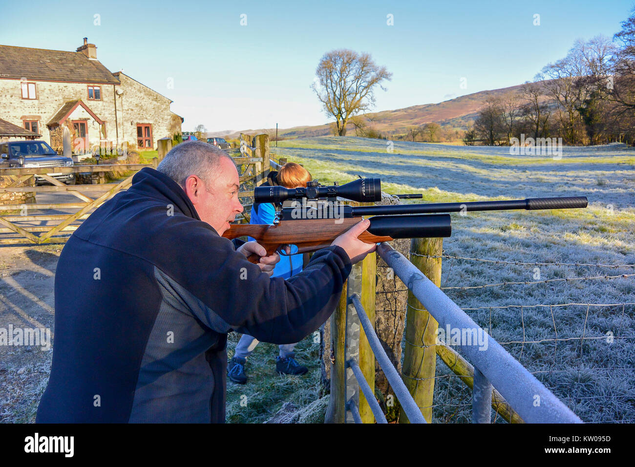 L'homme et adolescent tiré un fusil sur les terres agricoles sur l'air froid, un jour froid. Banque D'Images