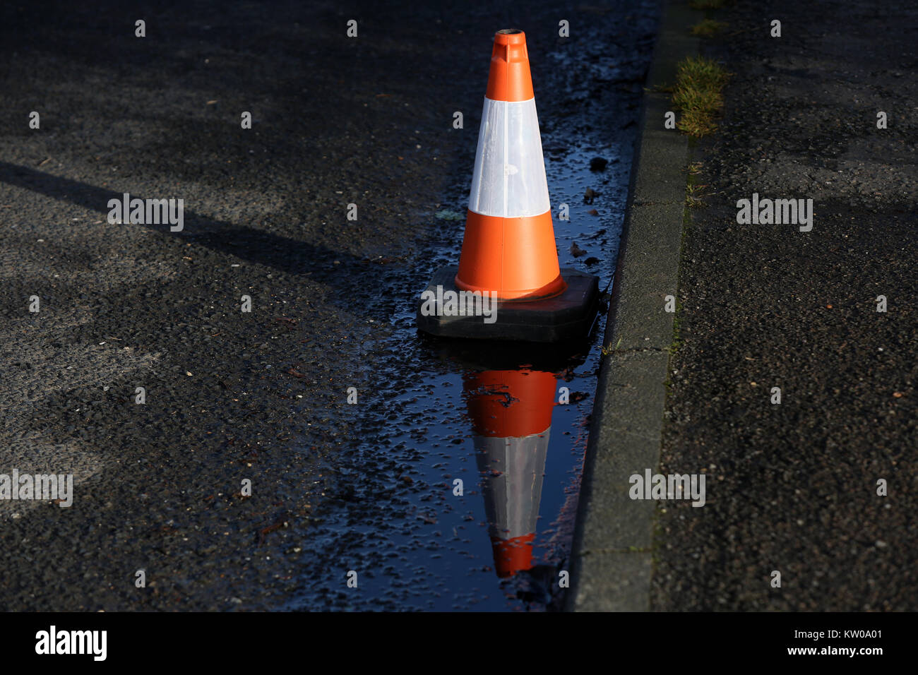 Un seul cône de trafic en photo avec reflet dans le West Sussex, Royaume-Uni. Banque D'Images