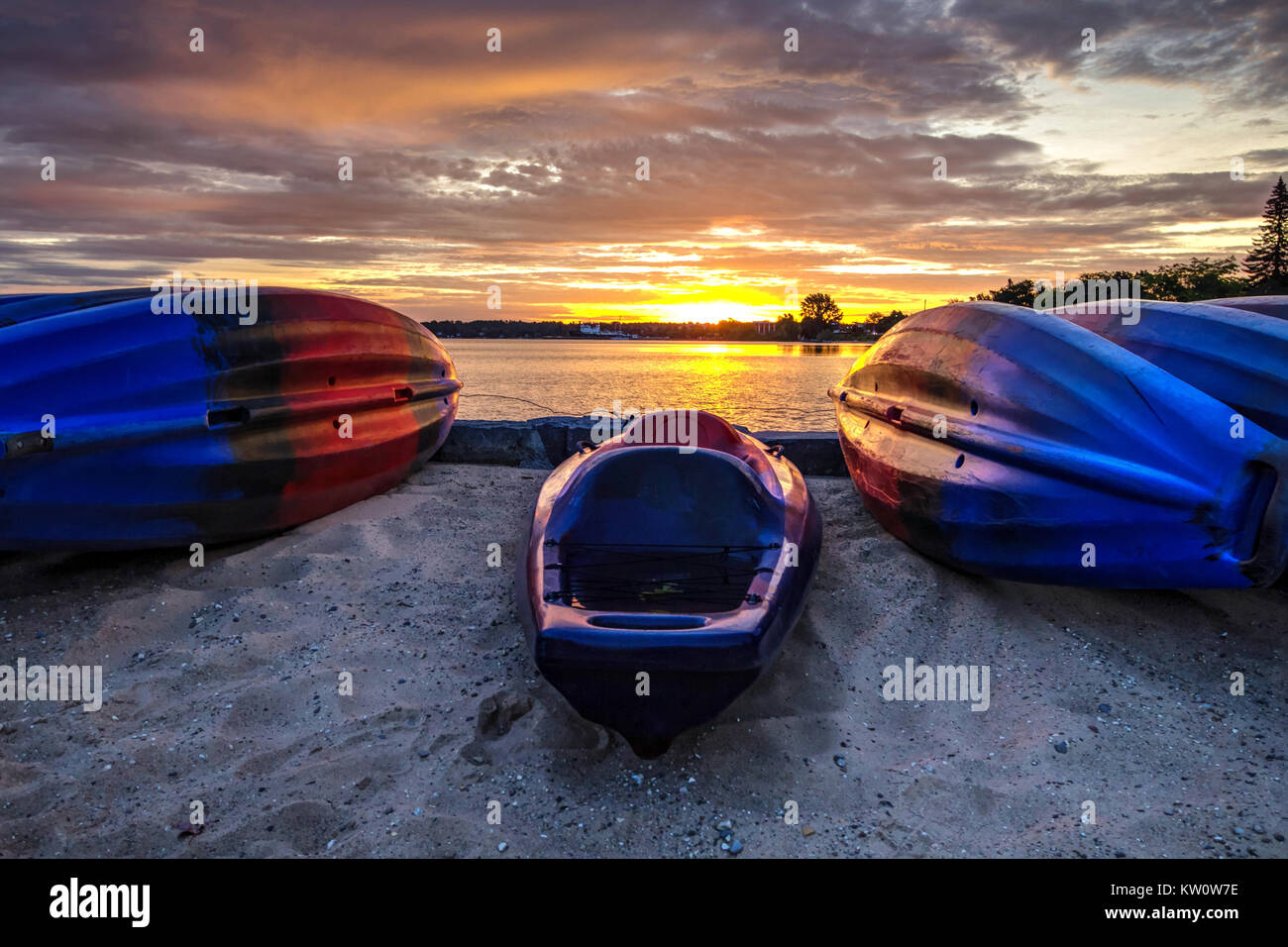 Kayak Le Lever du Soleil. Les kayaks sur une plage de sable fin au lever du soleil sur la côte des Grands Lacs du centre-ville de Traverse City (Michigan). Banque D'Images