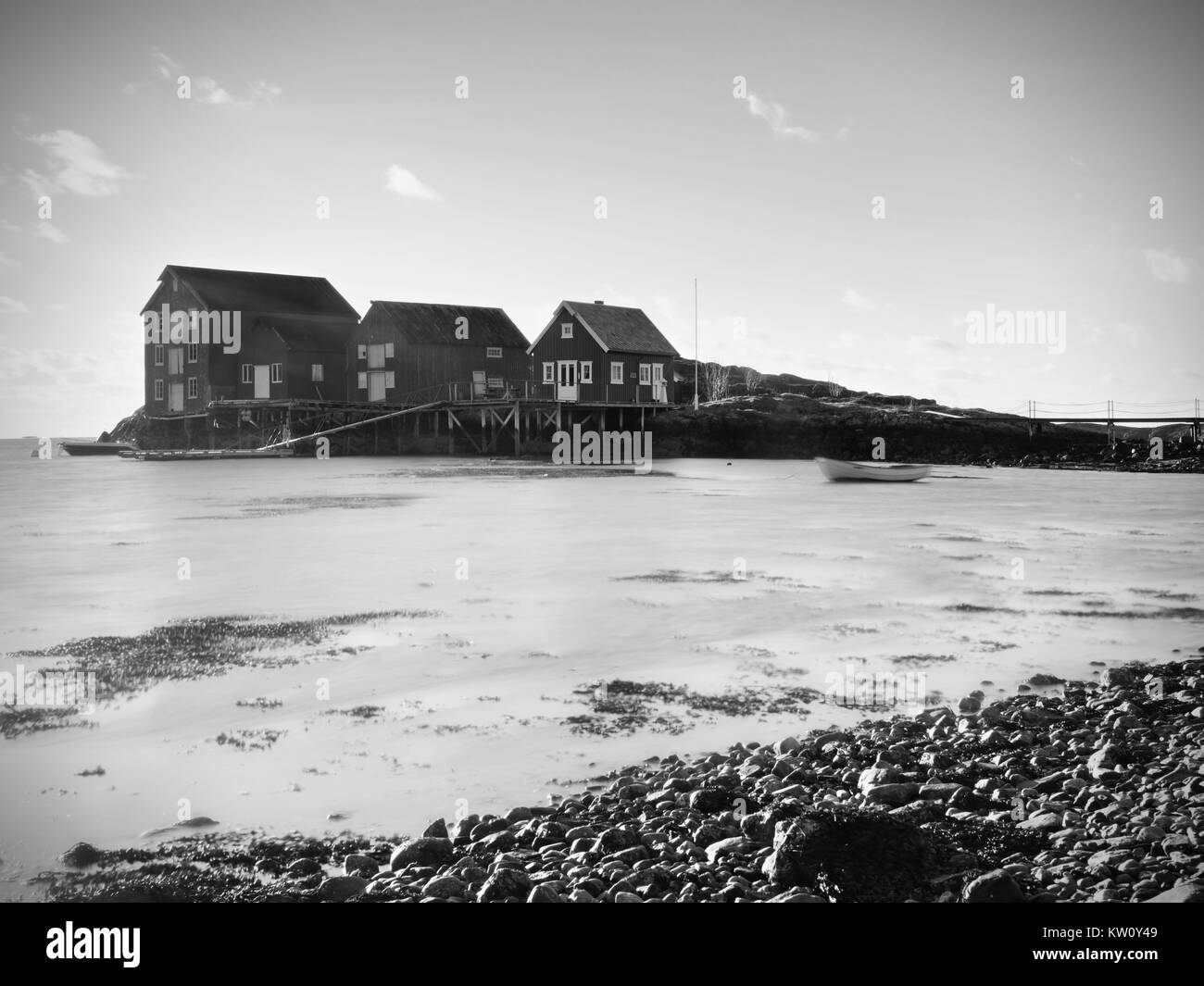 La Norvège village de pêcheurs sur l'île de pierre. Brillant rouge blanc maisons dans la baie tranquille. Niveau d'eau douce claire mise en miroir ciel cyan. Banque D'Images