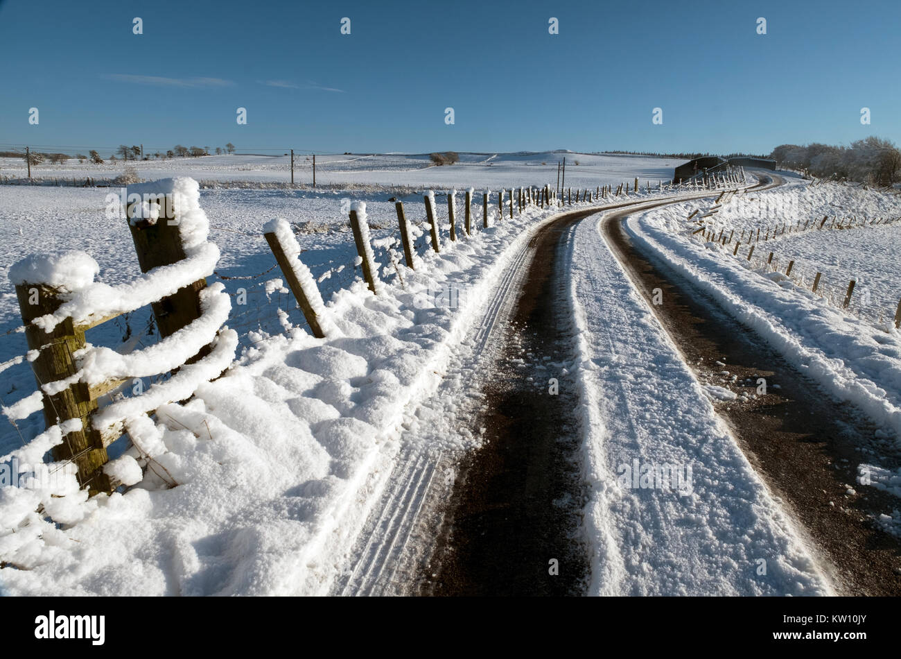 La neige a couvert retour route à travers les terres agricoles près de Forth, Lanarkshire, Écosse Banque D'Images