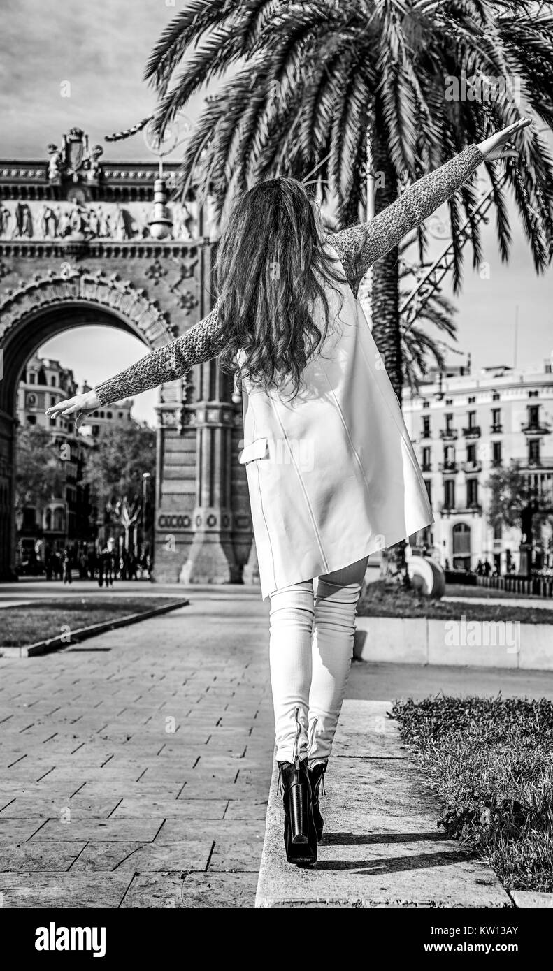 À Barcelone pour un hiver parfait. Vus de derrière, cheerful young fashion-monger dans des coquilles à Barcelone, Espagne La marche sur un parapet Banque D'Images