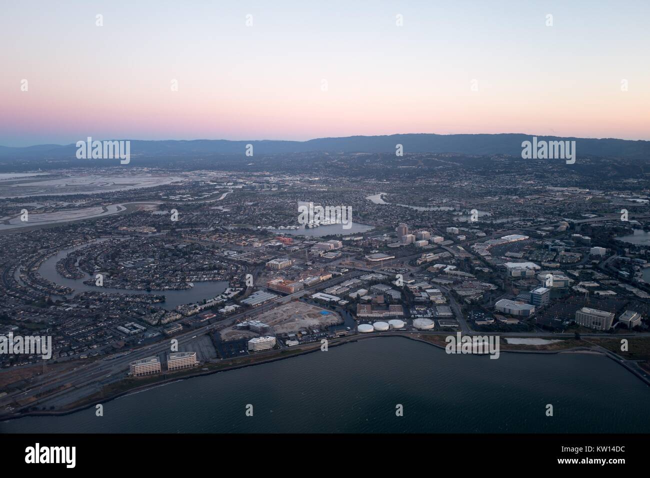 Vue aérienne de la Silicon Valley, au crépuscule, avec une partie de la San Mateo/Hayward Bridge visible, ainsi que de favoriser la ville, y compris la Californie, siège de Gilead Sciences, Visa, et Conversica, Californie, juillet 2016. Banque D'Images