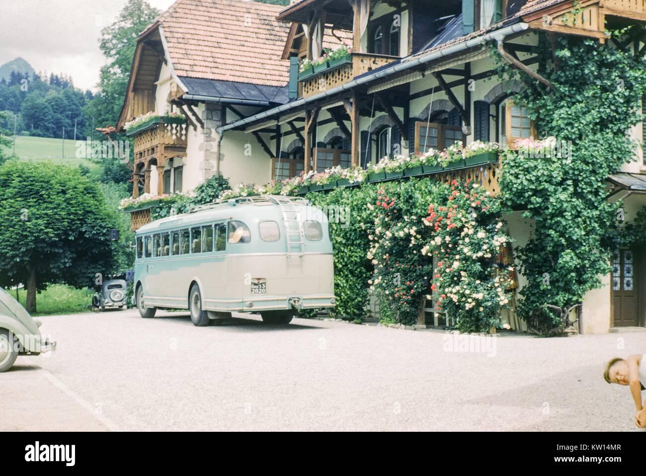 Bus touristique bleu et blanc garé en face de l'Hotel Geiger, un hôtel de style bavarois dans Fusssen, Allemagne, 1952. Banque D'Images