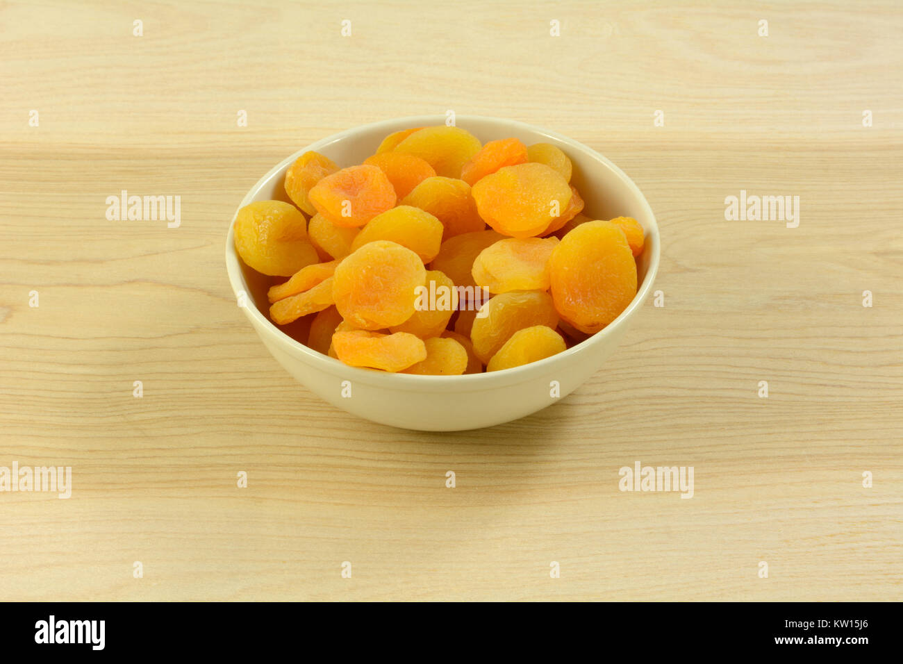 Abricots secs entiers en blanc bol snack sur table en bois Banque D'Images