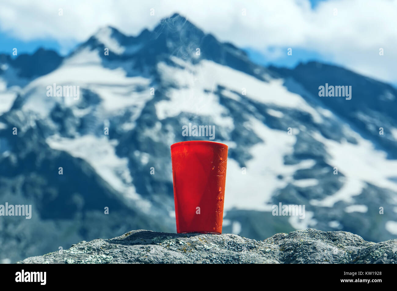 Orange un verre d'eau sur les pierres, sur fond flou belles montagnes. La notion de fraîcheur et de la pureté de la nature sauvage. Banque D'Images