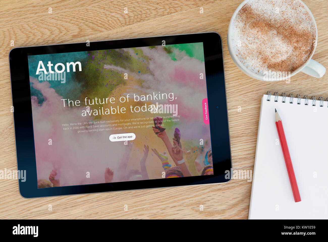 L'Atome site web d'une banque sur un iPad tablet device, reposant sur une table en bois à côté d'un bloc-notes, crayon et tasse de café (rédaction uniquement) Banque D'Images