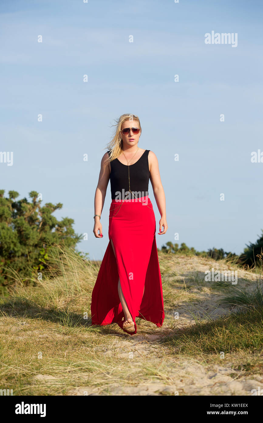 Belle fille blonde portant une longue jupe rouge avec un groupe et noir  haut dans les dunes de sable Photo Stock - Alamy