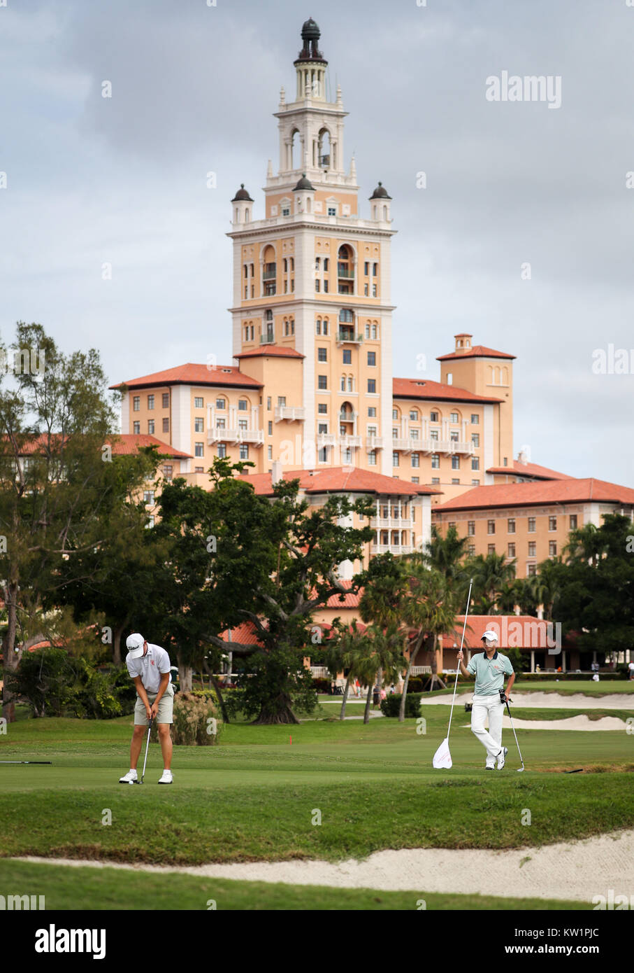 Coral Gables, en Floride, aux Etats-Unis. 28 Dec, 2017. Le Biltmore Hotel sert d'arrière-plan comme Jerry Ji (Pays-Bas), tandis que les putts Hirata Kensei (Japon) tient le drapeau sur un green, à la 54ème International Junior Orange Bowl Golf Championship au Biltmore à Coral Gables, en Floride. Mario Houben/CSM/Alamy Live News Banque D'Images