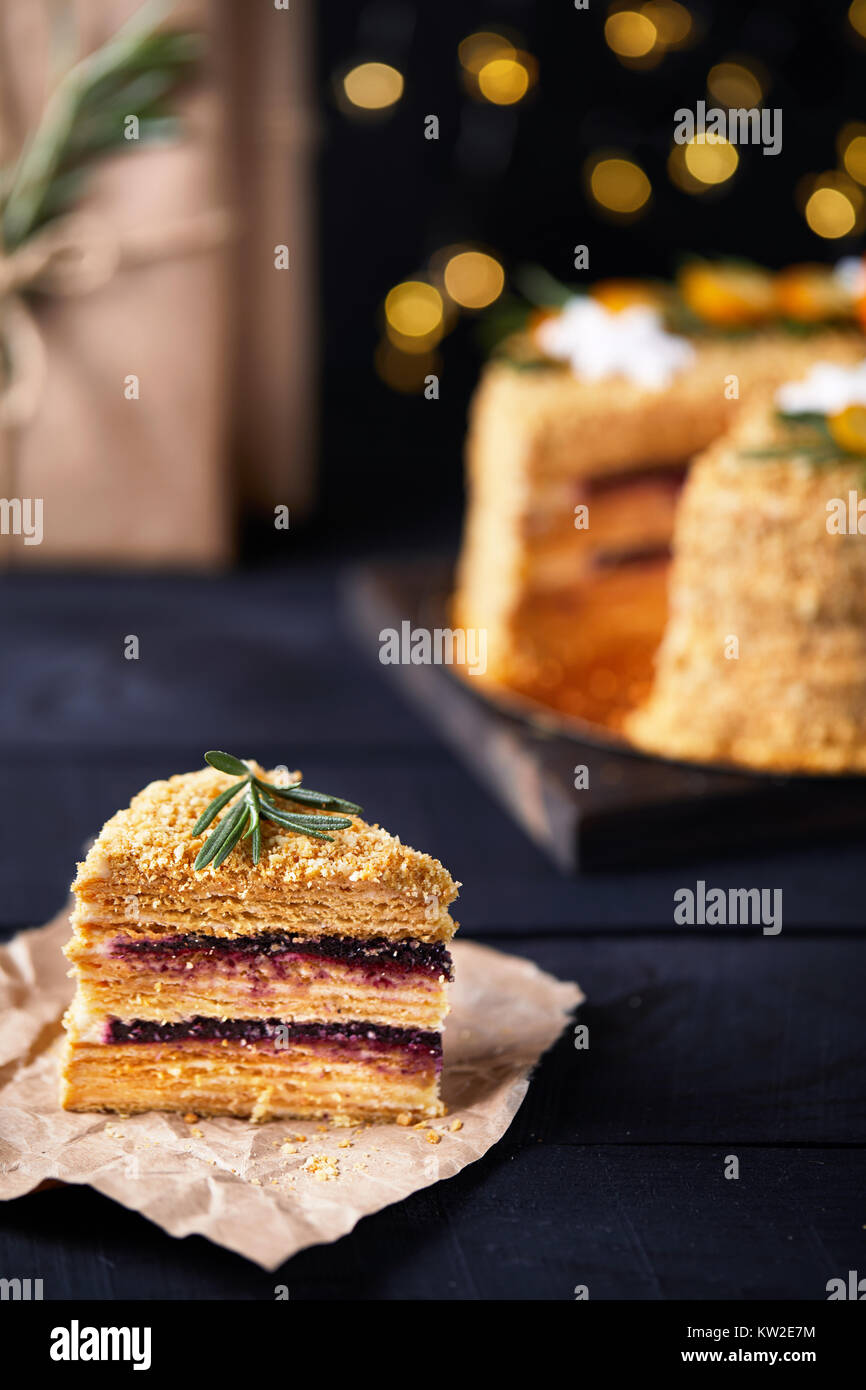 Morceau de gâteau au miel de Noël avec le romarin et oranges sur fond noir. Banque D'Images