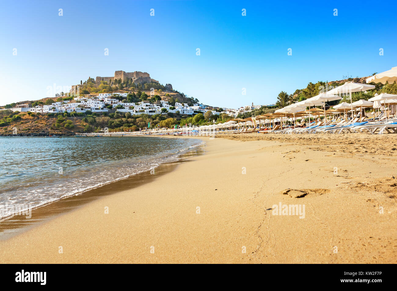 Vue sur plage de sable fin dans la baie de Lindos, Acropole en arrière-plan (Rhodes, Grèce) Banque D'Images