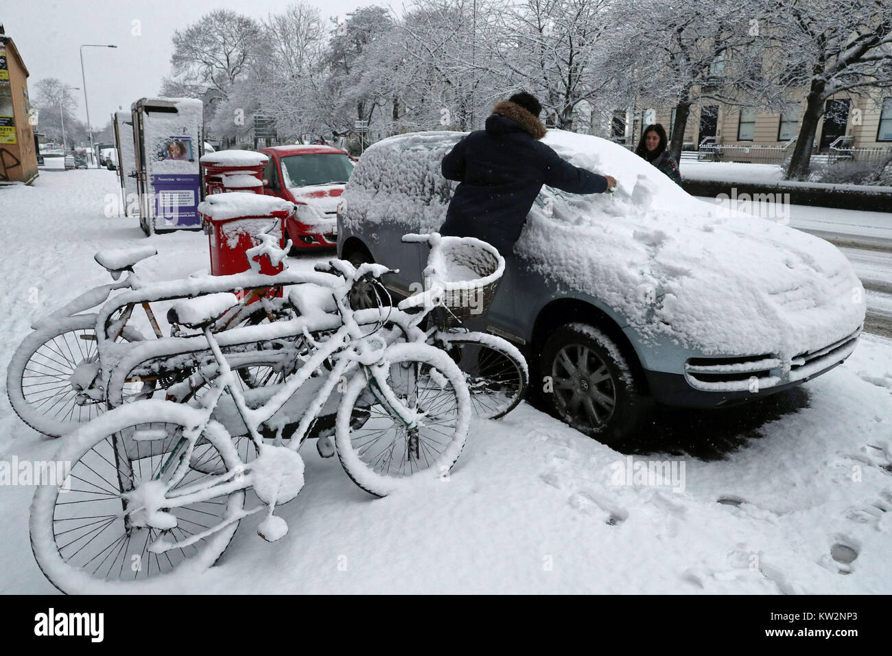 Un couple déblayer la neige de leur voiture à Glasgow, que la Grande-Bretagne a vu l'une des nuits les plus froides de l'année avec des températures à la baisse pour atteindre moins 12.3C à Loch Glascarnoch dans les Highlands écossais. Banque D'Images