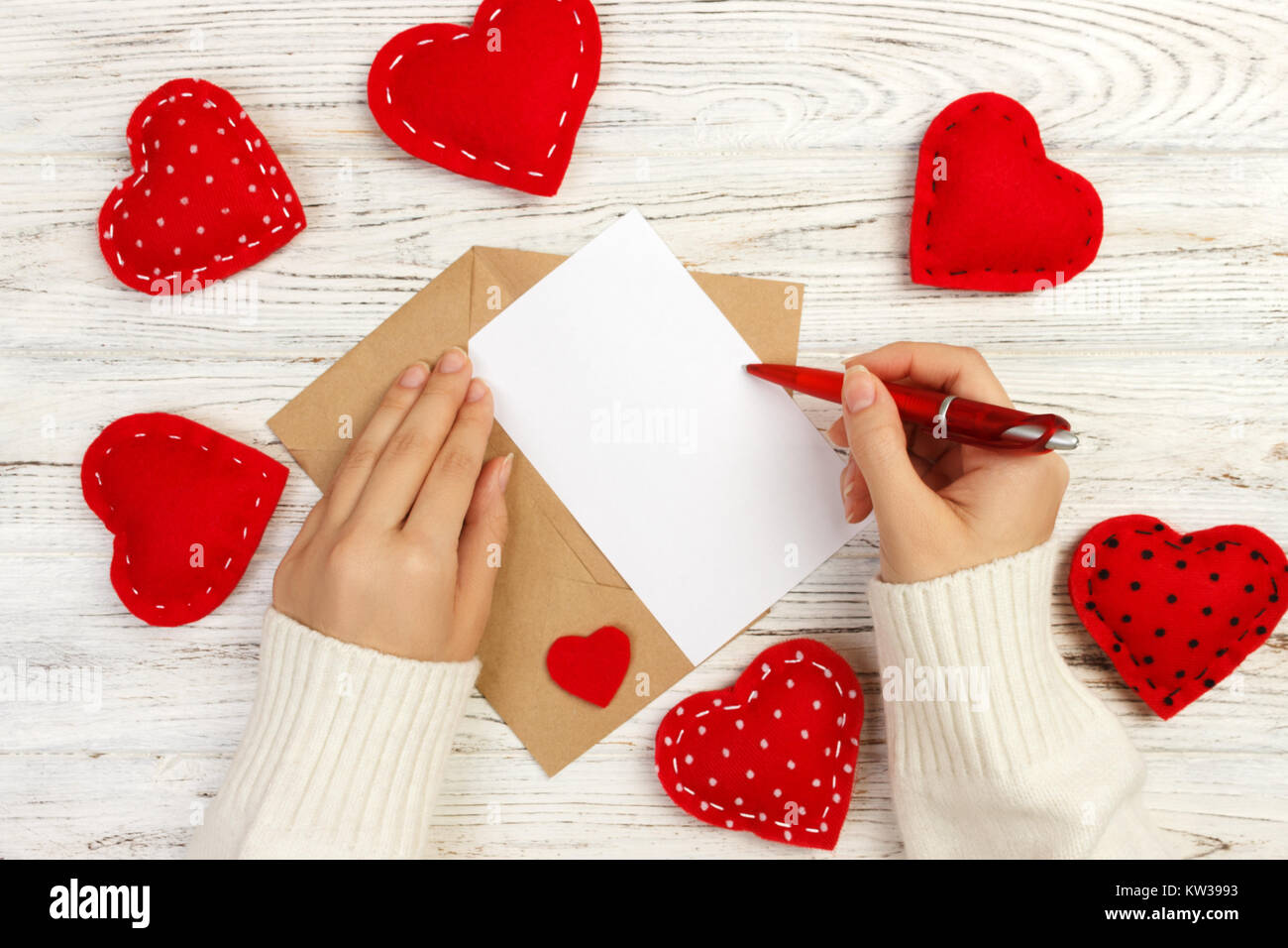 Main de fille écrit Lettre d'amour pour la Saint Valentin 24. Carte postale  à la main. Femme écrire sur une carte postale pour le 14 février fêtes.  Mise à plat. Vue d'en