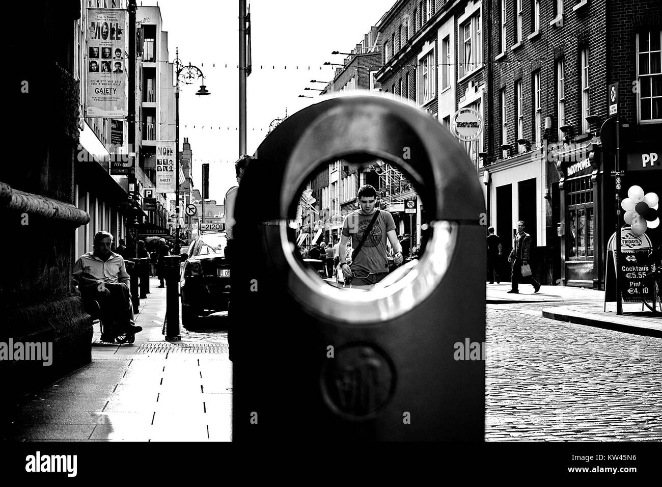 Cette photographie en noir et blanc représente une personne dans un environnement urbain. L'image capture le sujet dans un cadre urbain, véhiculant probablement un sentiment de solitude ou de contemplation. Le style monochrome met l'accent sur les ombres et le contraste, typique de l'art photographique axé sur les sujets humains dans les espaces urbains. Banque D'Images