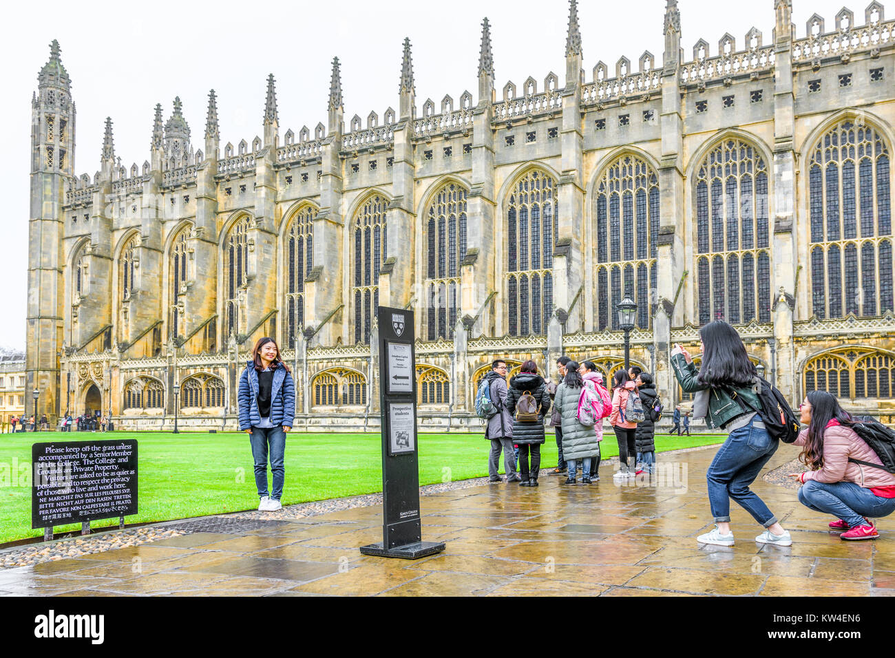 Les touristes chinois dans la cour avant avec la chapelle derrière eux un jour de pluie au King's College, Université de Cambridge, en Angleterre. Banque D'Images