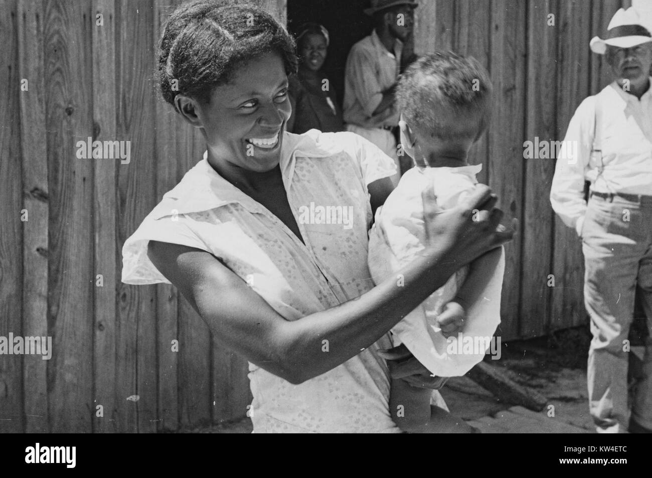 Demi-longueur franc portrait de l'épouse d'un fermier souriant et tenant son jeune enfant, de Tupelo, Mississippi, Août, 1935. À partir de la Bibliothèque publique de New York. Banque D'Images