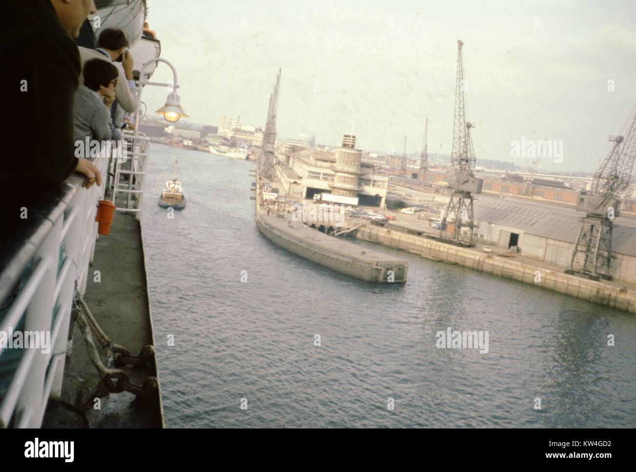Les passagers se pencher par-dessus les rails de la ligne Cunard Queen Elizabeth 2 navire de croisière à l'approche d'un port, 1975. Banque D'Images