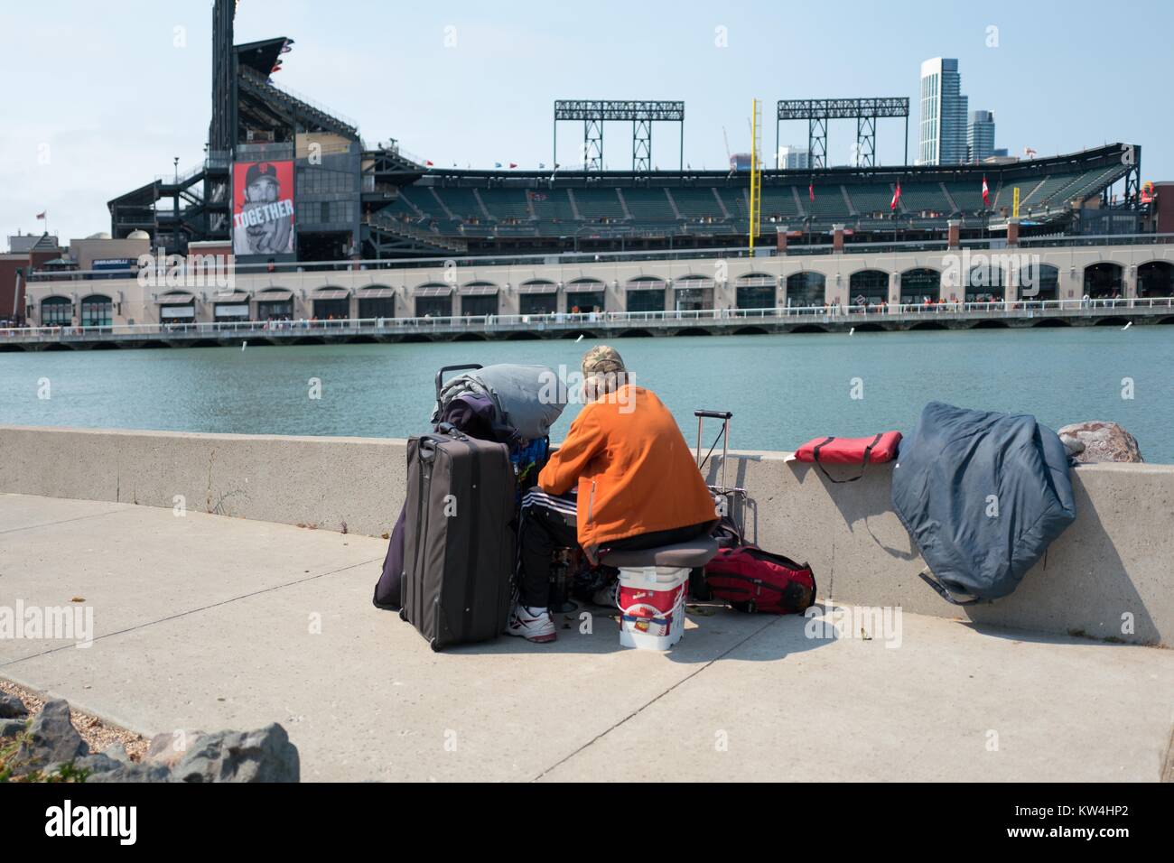 Un homme sans domicile fixe à travers McCovey Cove vers ATT Park, le stade de baseball des Giants de San Francisco, dans le quartier du bassin de la Chine de San Francisco, Californie, le 21 août 2016. Banque D'Images