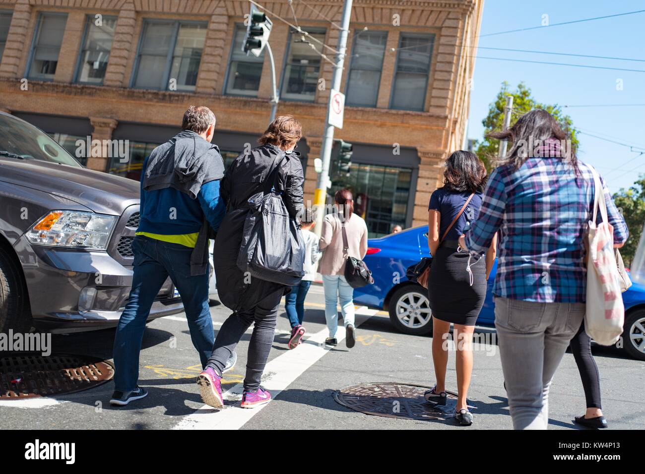 Un groupe de personnes à pied entre les voitures pour traverser une intersection à San Francisco, Californie, le 4 septembre 2016. Banque D'Images