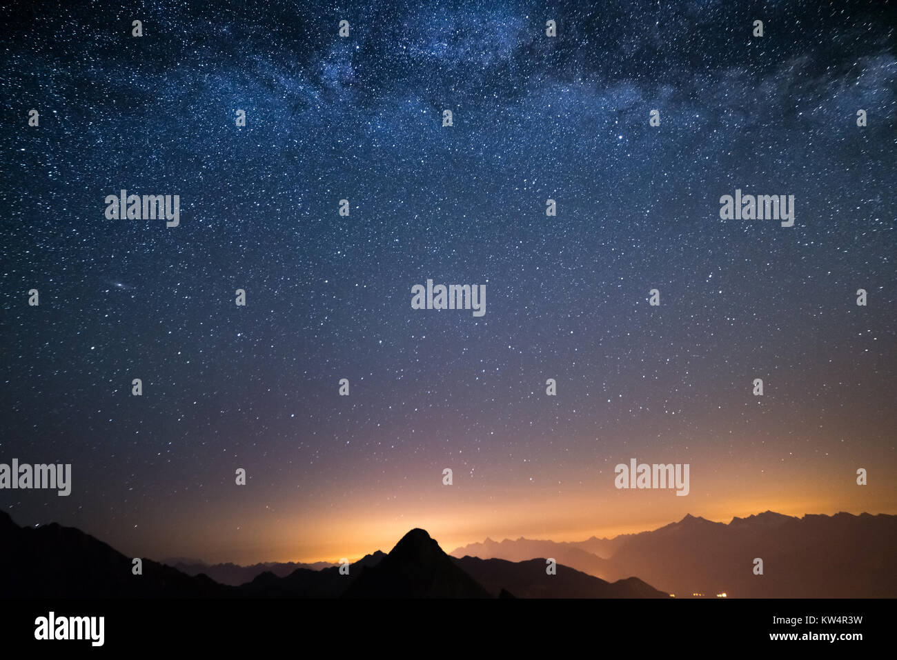 Le merveilleux ciel étoilé sur l'époque de Noël et la majestueuse chaîne de montagnes élevées des Alpes italiennes, avec des villages lumineux ci-dessous. Banque D'Images