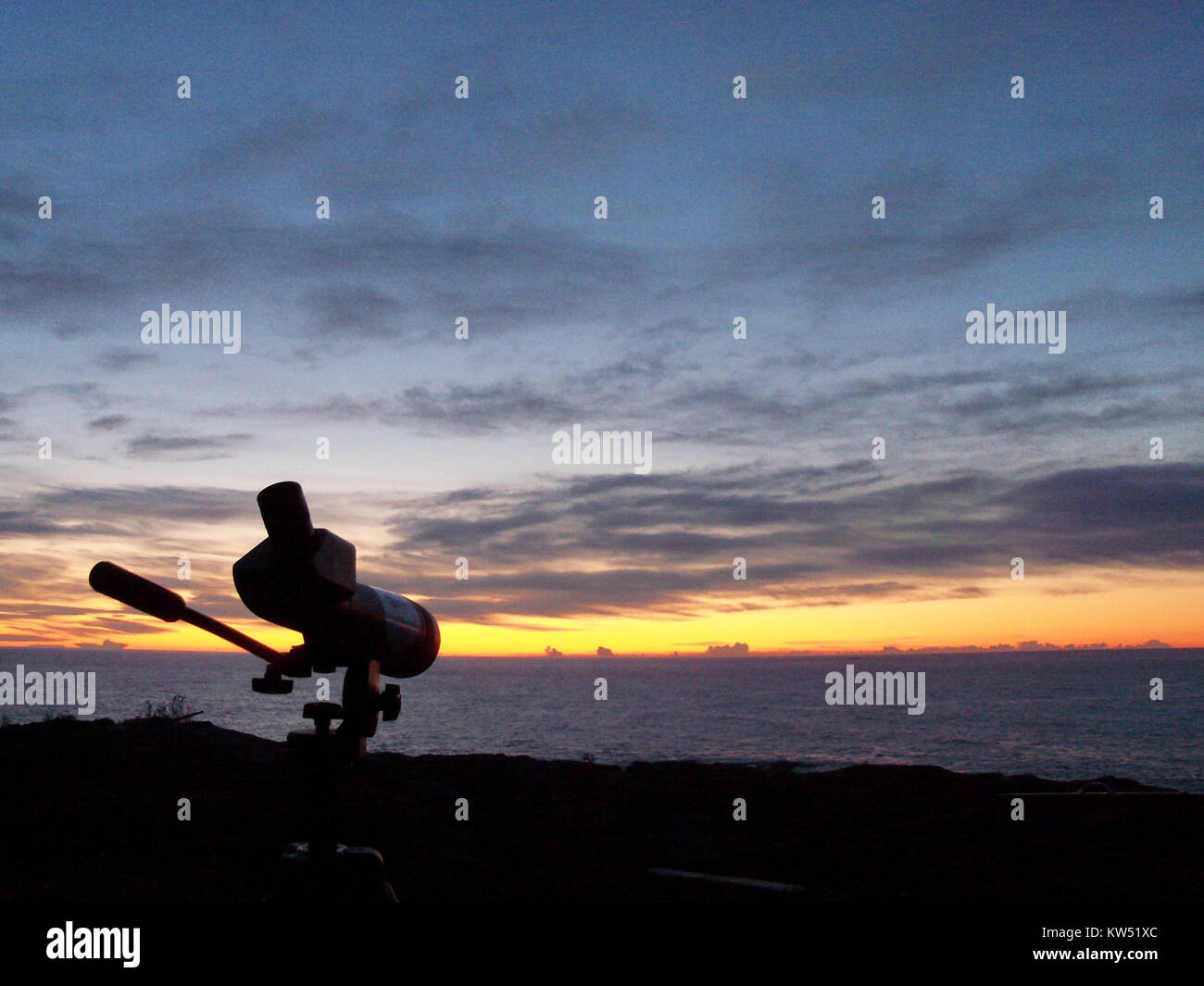 Observation des oiseaux au lever du soleil sur le cap sud de l'île Landsort en Suède, avec une lumière matinale illuminant le ciel et l'océan. La scène capture les oiseaux en vol et l'environnement côtier naturel. Banque D'Images