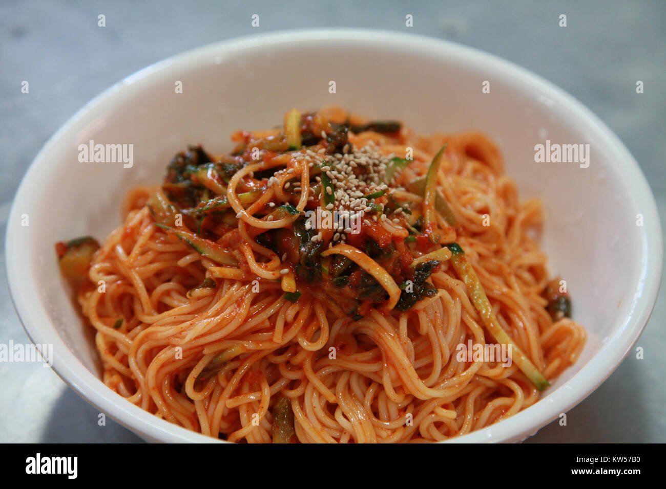 Le guksu Bibim est un plat coréen traditionnel composé de nouilles froides servies avec une sauce piquante et acidulée, souvent composée de légumes et de viande. C'est un repas d'été rafraîchissant et populaire en Corée. Banque D'Images