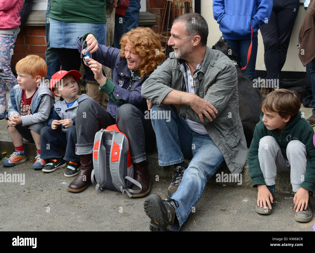 Family sitting in freiner regarder animations de rue l'homme vert au Festival d'Oisans dans le Shropshire Banque D'Images