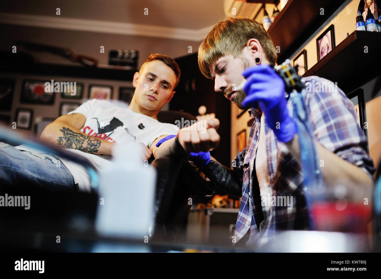 Tatoueur fait un nouveau tatouage pour un jeune mec Banque D'Images